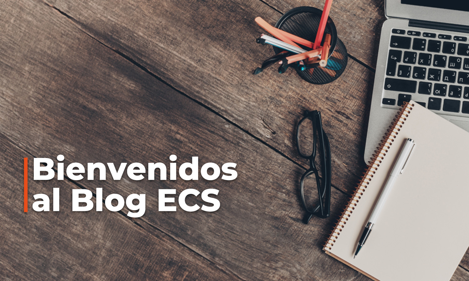 Welcoming banner text 'Bienvenidos al Blog ECS' on a wooden desk with laptop, notebook, glasses, and a pen.